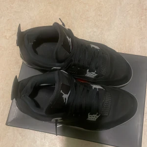 Svarta Nike Air Jordans - Säljer ett par svarta Jordan 4 black canvansi bra skick. De har en klassisk design med snörning och grå detaljer. Perfekta för både vardag och fest. Skorna är bekväma och stilrena, en riktig ikon i sneaker