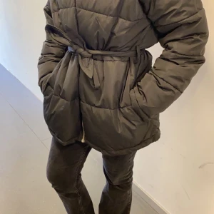 Svart pufferjacka från Nelly - Säljer en svart pufferjacka från Nelly i storlek 40. Jackan har ett bälte i midjan och långa ärmar, perfekt för kalla dagar. Den är i mycket bra skick och supermysig att ha på sig. Passar perfekt till både vardag och fest! 🖤