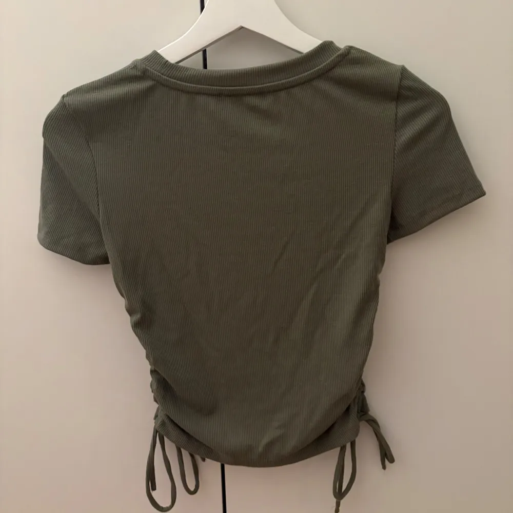 Snygg grön ribbad topp från Zara i mycket bra skick. Den har korta ärmar och en cool snörningsdetalj på sidorna som ger en fin passform. . Yläosat.