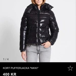Kort svart pufferjacka 'Nikki' - Säljer en snygg och glansig svart pufferjacka 'Nikki'. Den är i storleken xs som är helt slutsåld. Helt oanvänd och lappen är kvar❤️