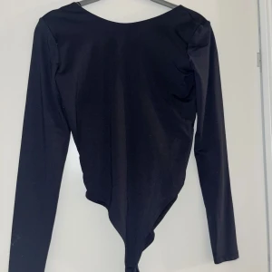  långärmad body från Zara - Snygg mörkblå graffiti body från Zara i storlek S. Den har öppen rygg och långa ärmar, perfekt för både vardag och fest. Materialet är mjukt och stretchigt för en bekväm passform!💙