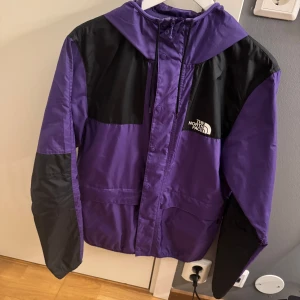 Lila och svart jacka från The North Face - Säljer en snygg lila och svart jacka från The North Face. Jackan har en huva och dragkedja framtill. Perfekt för höst och vår med sin lätta och bekväma passform. Den är i mycket bra skick och redo för nya äventyr!