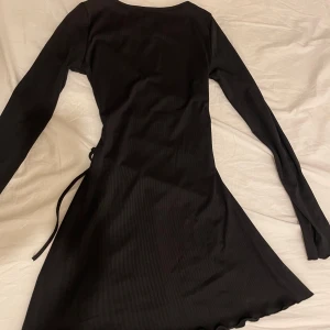 Svart ribbad klänning med snörning - Jätte fin svart klänning med snörning där bak för att midjan ska framhävas, helt oanvänd