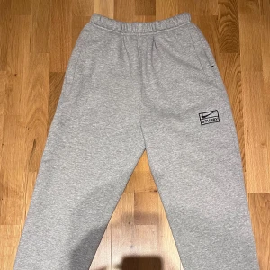 Nike x Stussy mjukisbyxor - Säljer ett par grå Nike x Stussy mjukisbyxor. Byxorna har använts 1-2 gånger och är i princip nyskick. Sitter ganska baggy men blir tajtare vid fötterna.