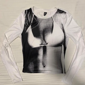 Vit och svart långärmad topp från Shein - Cool och unik långärmad topp från Shein i vitt och svart med ett häftigt tryck. Perfekt för att sticka ut på festen eller bara ha en chill dag. Materialet är mjukt och stretchigt för en bekväm passform. 🖤🤍