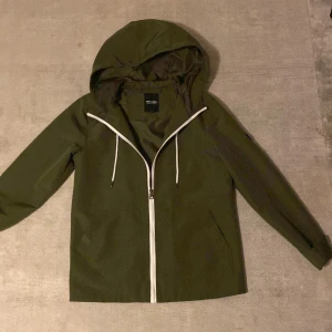 Grön vindjacka från Only & Sons - Tja, Säljer en snygg grön vindjacka från Only & Sons i storlek XS men skulle rekommendera den till dig som har storlek S. Jackan har en praktisk huva och dragkedja framtill. Perfekt för hösten och dem mildare vinterdagarna. Jackan är i mycket bra skick och passar till både vardag och lättare utomhusaktiviteter. 