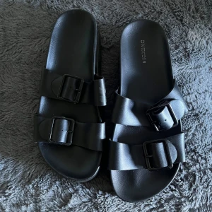 Fina tofflor - Svarta tofflor från Divided. Använda några gånger men fortfarande bra skick💗 bekväma men små i storlek