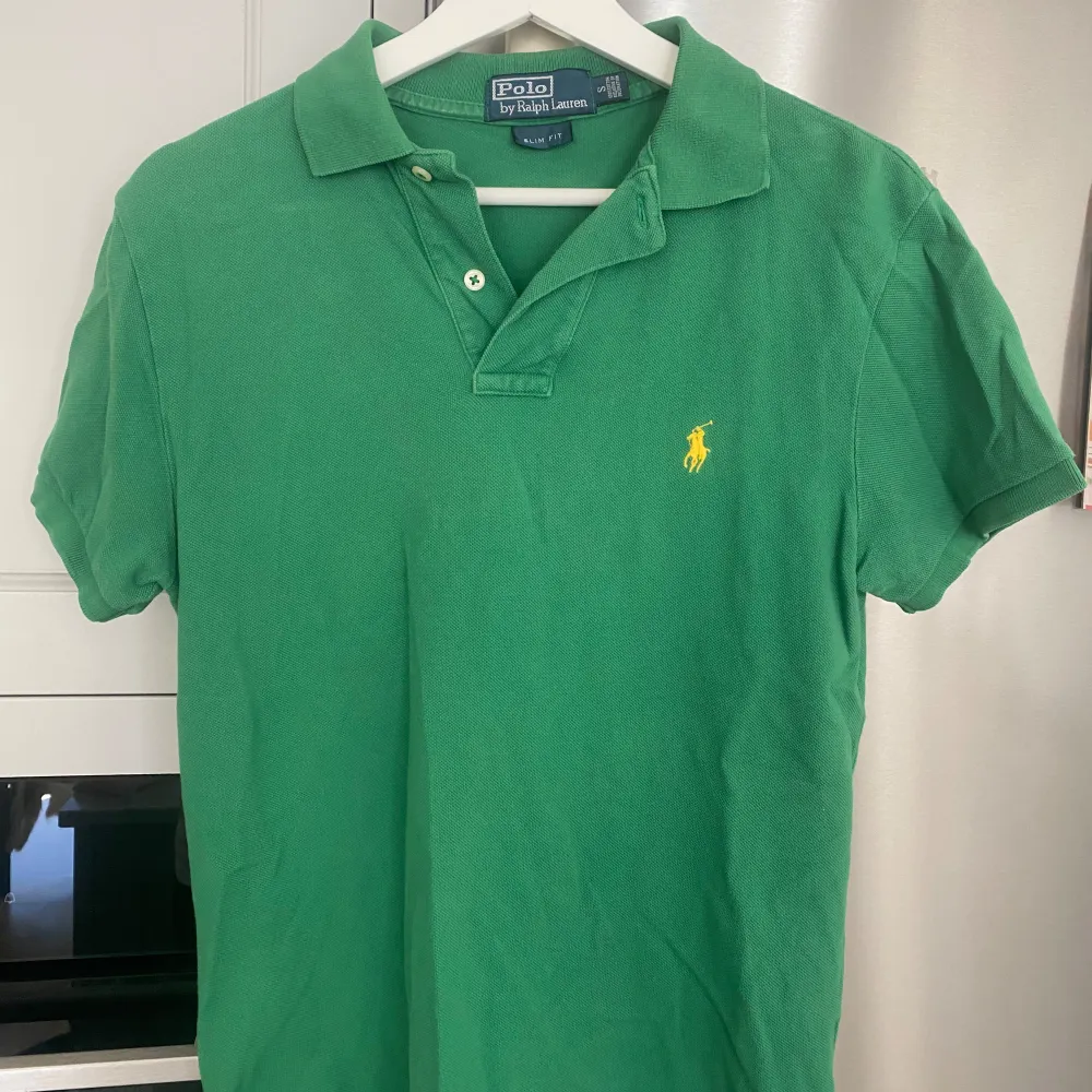 Säljer en snygg och tidlös grön pikétröja från Polo Ralph Lauren i storlek S. Tröjan är slim fit och är gjord av bomull. I bra skick, något urtvättad. T-shirts.