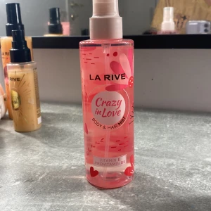 Crazy in Love Body & Hair Mist från La Rive - Säljer en fräsch och härlig body & hair mist från La Rive med namnet Crazy in Love. Den kommer i en genomskinlig rosa flaska med ett sprutmunstycke. Innehåller vitamin E och provitamin B5 för extra vård. Perfekt för att fräscha upp både kropp och hår med en underbar doft. Flaskan rymmer 200 ml (6.7 fl oz).