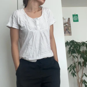 Vit kortärmad blus från Flash Woman - Säljer en söt vit blus från Flash Woman i storlek M. Blusen har korta ärmar och en fin detalj med knappar framtill. Perfekt för både vardag och fest!