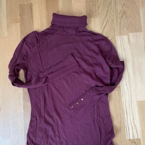 Mörkröd polotröja med gulddetaljer - Mörkröd finsnickare polotröja med guldknappar. Storlek L men passar även S