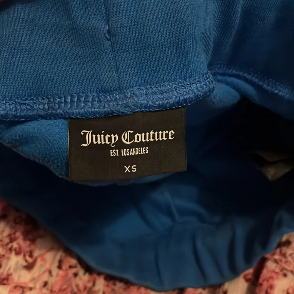 Säljer ett par supermysiga blå mjukisbyxor från Juicy Couture i storlek XS. Byxorna har en skön passform med snörning i midjan och praktiska fickor med knappar. Perfekta för en chill dag hemma eller en avslappnad promenad. De är i bra skick och redo för en ny ägare!. Jeans & Byxor.