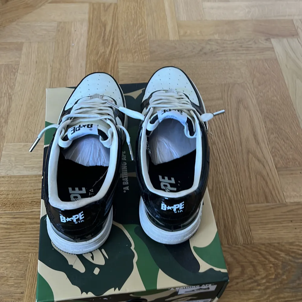 Säljer ett par snygga svartvita sneakers från BAPE. Skorna är i nyskick och har en cool design med en stjärna på sidan. De är gjorda av syntetmaterial och har snörning framtill. Priset kan diskuteras! Vid snabb affär 850kr. Skor.