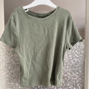 Grön ribbad t-shirt - Säljer en snygg grön ribbad t-shirt. Den är kortärmad och har en normal passform. Perfekt för vardagsbruk eller att matcha med ett par jeans för en avslappnad look.