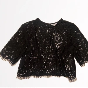 Svart spets blus  - Snygg spetsblus med korta ärmar och en fin spetskant. Blusen har en knappstängning i ryggen. Blusen är i storlek XL men passar perfekt på mig som har storlek S i alla kläder. 