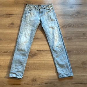 Ljusblå jeans från Jack & Jones - Säljer ett par ljusblå jeans från Jack & Jones med en tapered passform. De har en klassisk femficksdesign och knappar i gylfen. Perfekta för en avslappnad stil. waist 31 lengt 34 