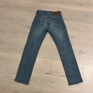 Blå jeans från Levi's - Säljer ett par klassiska blå Levi's jeans i modell 501. De har en straight passform och är tillverkade i slitstarkt denim. Perfekta för en avslappnad stil med fem fickor och knappgylf.