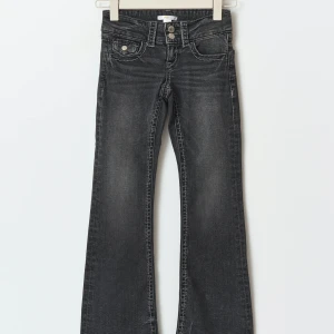 Mörkgråa bootcut jeans - Snygga mörkgråa bootcut jeans med en klassisk femficksdesign och dubbla knappar i midjan. Jeansen har en lätt tvättad look som ger en cool vintagekänsla. Perfekta för en avslappnad stil.