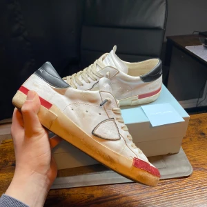Philippe model skor - Snygga och bekväma Philippe Model sneakers i storlek 41! Perfekta för både vardag och mer uppklädda tillfällen | Färg: Vit med röda detaljer ⚪🔴 | Skick: Bra skick, endast lätt använda 👍 | Storlek: EU 41 (ungefär en storlek större) 🙌| Box, äkthets bevis och creaseskydd ingår🙌  📦 | Leverans: Skickas snabbt via PostNord eller instabox |  💬 Skicka ett meddelande vid frågor!