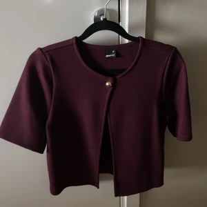One button top - Snygg vinröd topp från Gina Tricot med en elegant knapp framtill. Det är rekvartsärm och en stilren design. Perfekt för att lyfta vilken outfit som helst