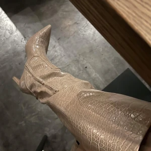 Beige stövlar  - Säljer mina sypersnygga beige stövlar med krokodilpräglat mönster och spetsig tå då dessa tyvärr inte längre kommer till användning. Köpta för 699