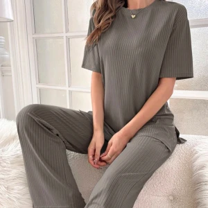 Grå ribbad set med kortärmad topp - Snyggt och bekvämt grått set med ribbad design. Toppen är kortärmad och byxorna har en slits vid anklarna. Perfekt för en avslappnad stil och lounge! 