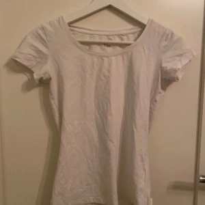 Vit kortärmad topp från Lindex - Säljer en enkel och stilren vit topp från Lindex i storlek XS. Toppen har korta ärmar och en rund halsringning, perfekt för en avslappnad look.