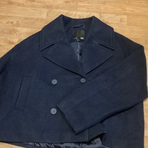Mörkblå skepparkavaj - Snygg mörkblå skepparkavaj från Lager 157 i storlek M. Jackan har en klassisk dubbelknäppning med stora knappar och en stilren krage. Perfekt för kyligare dagar med sitt inre material. En tidlös stil som funkar till många tillfällen.