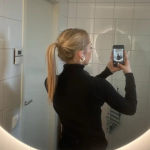 Svart ribbad polotröja från Tracy M. - Säljer en stilren svart ribbad polotröja från Tracy M. Tröjan har en tight passform och långa ärmar, perfekt för kyligare dagar. Tillverkad i en mjuk bomullsblandning med lite stretch för extra komfort. Passar utmärkt till både jeans och kjol. 🖤