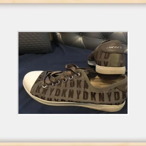  sneakers från DKNY i storlek 37, 5 - Snygga sneakers från DKNY med logotypmönster. Skorna har lite skavanker som syns på bild därav låga priset. Skorna är tvättade såklart! 