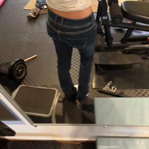 Mörkblå jeansbyxor - Snygga mörkblå jeans med en tight passform och låg midja. Perfekta för en avslappnad stil. Klassisk design med fickor och knappdetaljer.