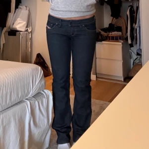 Blå jeans från Diesel - Snygga blå jeans från Diesel med bootcut-stil och låg midja. De har coola dragkedjedetaljer på bakfickorna. Ena fickan saknar ”pärlor”. Superbra skick❣️