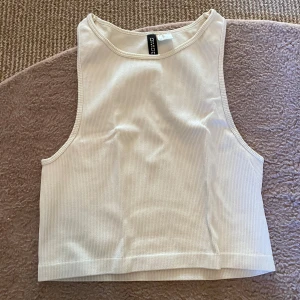 Topp - Snygg vit ribbad linnetopp från H&M Divided. Perfekt för varma dagar med sin ärmlösa design och croppade längd. Enkel och stilren, passar till det mesta i garderoben😻Bra basplagg att ha❤️