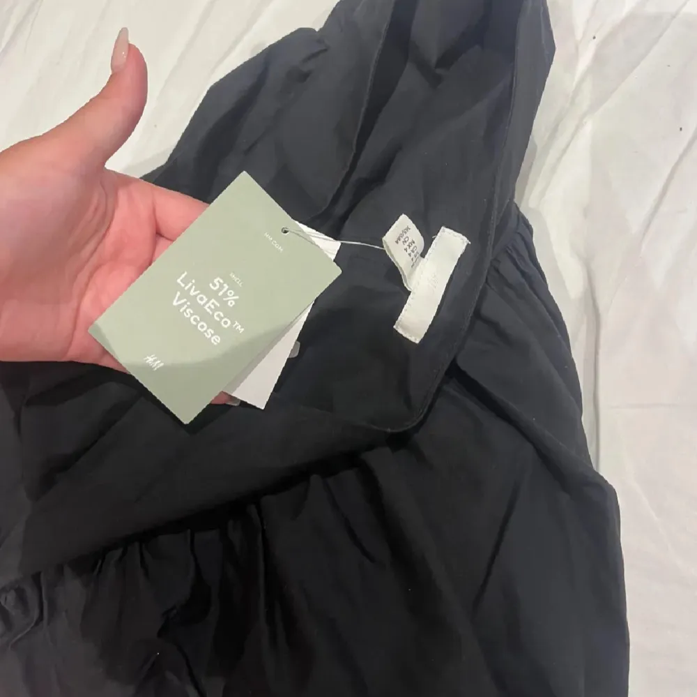 Snygg svart kjol från H&M i viskos med en voluminös design. Kjolen har en bred midja och en luftig passform som ger en avslappnad look. Perfekt för att skapa en stilren outfit.. Hameet.
