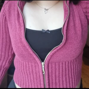 Rosa stickad kofta med dragkedja - Säljer en mysig rosa stickad kofta med dragkedja framtill. Koftan har långa ärmar och ribbade detaljer vid ärmslut och nederkant. Perfekt för kyliga dagar!