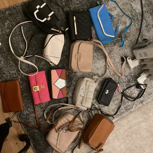 Samling av olika väskor - En samling av olika väskor i varierande färger och stilar. Här finns en blå axelväska, en quiltad svart väska, en beige handväska och en rosa plånbok med gulddetaljer. Perfekt för den som vill ha flera alternativ för olika tillfällen.Varje väska kostar 40 kr, men om du tar 3 blir priset 109kr.