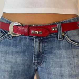 Rött bälte med nitar - Snyggt rött bälte med silverfärgade nitar och ett mönstrat yttre. Bältet har ett stilrent spänne i silver och passar perfekt till jeans. Ett coolt tillbehör för att lyfta din outfit! 💞💞