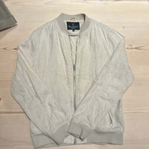 Beige bomberjacka i linne från Bondelid - Säljer en stilren beige bomberjacka i linne från Bondelid. Jackan har en dragkedja framtill och ribbade muddar vid ärmslut och nederkant. Perfekt för en avslappnad look. Pris diskuterbart!🤩