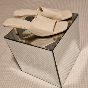 Vita sandaler med klack - Eleganta vita sandaler med klack och öppen tå. Perfekta för sommarens alla tillfällen. Stilren design med bred rem över foten.
