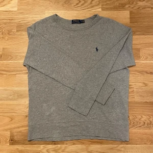 Grå stickad tröja från Ralph Lauren - Säljer en stilren grå tröja från Polo Ralph Lauren med deras ikoniska logga broderad på bröstet. Tröjan har långa ärmar och en klassisk rund halsringning. Perfekt för en avslappnad och snygg look. Riktigt bra skick och inga defekter eller liknande👍Stickad grå tröja med blå logga den är storlek S men passar också större. Pris diskuterbart vid snabb affär! 