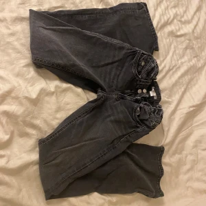 Svarta jeans från Gina Tricot - Snygga svarta jeans från Gina Tricot med klassisk femficksdesign och knappar i silverfärg. Perfekta för en avslappnad stil med en modern touch. Passar bra till olika outfits och tillfällen.