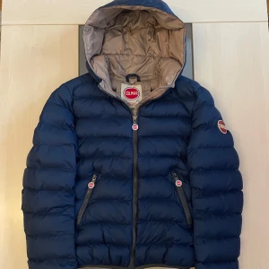 Blå pufferjacka från Colmar - Säljer en snygg blå pufferjacka från Colmar med huva och dragkedja. Köpt för 1900 kr på Plick men passar mig inte. Quiltad design, perfekt för kyla, med logga på ärmen och fickor med dragkedja. Modellen på bilden är 169 cm, 60 kg (jag är ej modellen). (Köpte jackan från Stockholmskläder, äkta eller fejk. Vet ej.) Öppen för rimliga prisförslag! 😁