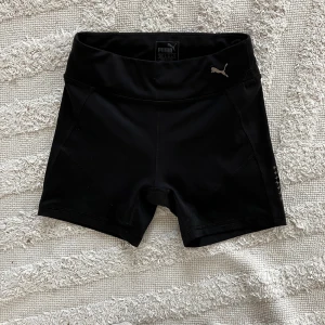 Svarta träningsshorts från Puma - Snygga svarta träningsshorts från Puma med hög midja och en liten logga på framsidan. Shortsen har en praktisk mobilficka baktill. 