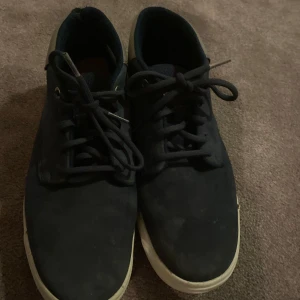 Mörkblå skor med vita sulor - Snygga mörkblå skor från Timberland med vita sulor och snörning. Perfekta för dig som vill ha ett par snyggare skor nu till vintern. Väldigt bra skick. Nypris 1999kr mitt pris 350kr. Pris kan diskuteras. Hör av dig vid funderingar!