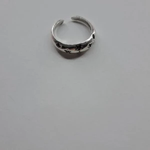 Silverfärgad ring med stjärndetaljer - Snygg och justerbar ring i silverfärg med ingraverade stjärnor runtom. Perfekt för att ge en extra touch till din stil. Passar de flesta fingrar tack vare den öppna designen. PRISET KAN DISKUTERAS
