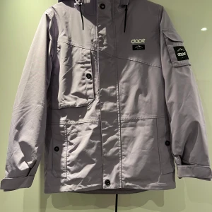 Ljuslila jacka från Dope - Säljer ett snowboard/skidset från Dope i färgen faded Violet. Jacka: Modell: Adept W med huva och flera praktiska fickor. Jackan stängs med både dragkedja och knappar. Byxor: Notorious B.I.B. W Säljes tillsammans eller var och en för sig. Använt ca 15 skiddagar så det är i gott skick. Nypris: 4298 kronor. Bonus: Finns även skidvantar från Hestra i matchande färg. 