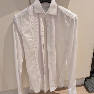 Vit smoking skjorta från John Henric stl 39 - Elegant vit smokingskjorta från John Henric i stl 39. Enbart använd en gång för bröllop. Perfekt skick!