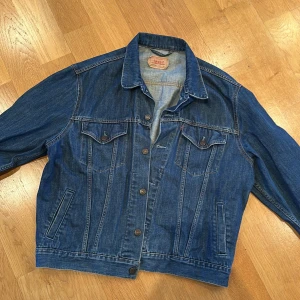 Jeansjacka från Levi's - Säljer en klassisk blå jeansjacka från Levi's med knappar framtill och två bröstfickor. Jackan har en tidlös design och är i storlek XL.