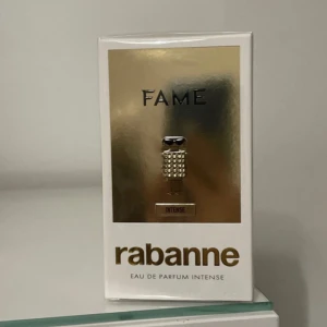 Fame Eau de Parfum Intense från Rabanne -  Fame Eau de Parfum Intense från Rabanne, en lyxig doft i en elegant förpackning. Flaskan har en unik design med guldiga detaljer som utstrålar glamour och stil. Den kommer dessutom i 30ml