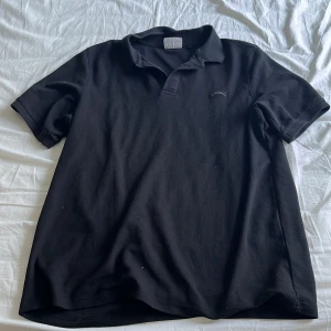 Svart kortärmad pikétröja - Snygg svart pikétröja med krage och korta ärmar. Perfekt för en avslappnad stil. Passar bra till jeans eller chinos.